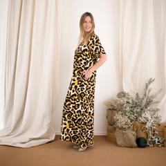 Modelo luciendo un vestido largo con estampado de leopardo, con fondo claro y decoraciones naturales.