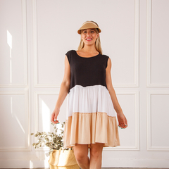Modelo usando un vestido de tres colores: negro, blanco y beige, en un entorno luminoso.