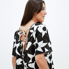 Vestido Nuez de fondo blanco y negro con detalles florales, visto desde el lado, mostrando el diseño de la espalda.