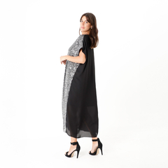 Mujer posando con un vestido largo negro con detalles brillantes en un costado.