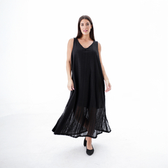 Mujer usando un vestido negro largo con tirantes en un fondo blanco.