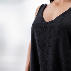 Detalle de un vestido negro de corte elegante, con un diseño texturizado y escote en forma de V.