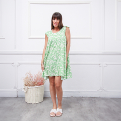 Modelo luciendo un vestido verde claro con estampado floral en un ambiente minimalista.