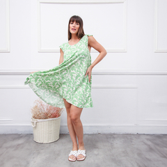 Vestido Sia verde con estampado de hojas, modelo con tirantes, en un entorno minimalista.