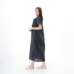 Vestido largo negro con rayas, modelo de pie, usando sandalias blancas.