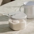 Açucareiro Break Branco com tampa e colher, contendo açúcar, ao lado de uma caneca branca em uma mesa com toalha clara.
