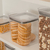 Pote hermético transparente com biscoitos empilhados em uma prateleira de cozinha.