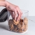 Pote hermético retangular transparente com biscoitos dentro, sendo retirado por uma mão.