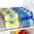 Porta latas organizador transparente com latas de refrigerante e cerveja na geladeira.