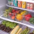 Organizadores multiuso transparentes com frutas e vegetais dentro de uma geladeira.