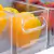 Organizadores multiuso de plástico transparente com frutas, mostrando uma laranja dentro de um compartimento.
