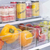 Conjunto de organizadores multiuso em geladeira, com frutas e bebidas em recipientes transparentes.