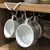 Porta xícaras móvel branco com xícaras brancas penduradas em um armário de cozinha