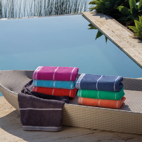 Toallones Jean Cartier de varios colores y rayas junto a una piscina.