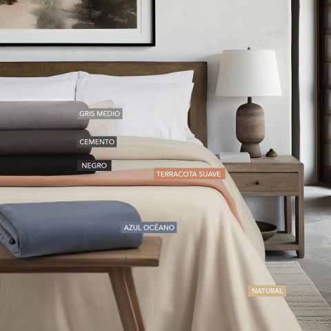 Frazadas de microfibra en varios colores sobre una cama en un dormitorio moderno.