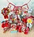 Decorações de festa Chapeuzinho Vermelho, incluindo caixas, etiquetas e enfeites com cores vibrantes e personagens infantis.