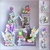 Decoração de festa Tinkerbell com elementos como fadas, sapos e cogumelos em tons de roxo e verde, ideal para festas de meninas.