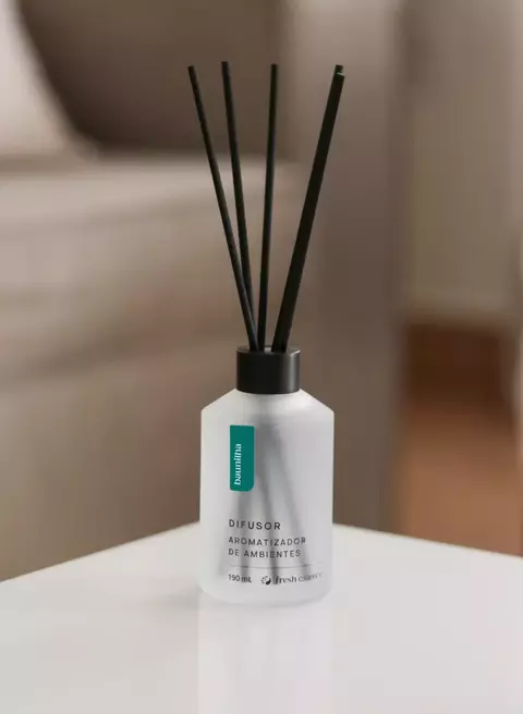 Difusor de varetas com fragrância de baunilha em frasco branco fosco com varetas pretas sobre superfície branca