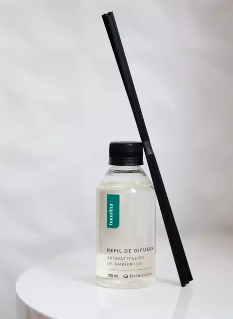 Refil de difusor de varetas com fragrância de baunilha, contendo líquido transparente em frasco com tampa preta e varetas pretas ao lado