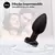 Plug anal vibrador impermeable de silicona grado médico en color negro, sumergido parcialmente en agua, con un fondo de pareja feliz.