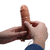 Arnés strapon con dildo macizo y vibración, siendo sostenido por manos. Ideal para juegos íntimos.