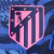 Terceira Camisa do Atlético de Madrid 2024/2025: azul marinho com grafismo vibrante. Destaques incluem o tridente de Netuno, Nike Swoosh rosa e escudo do Atleti em azul e rosa.