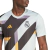 Camisa Pré-Jogo Real Madrid 2023 da Adidas Masculina. A camisa é predominantemente Wonder Silver com detalhes em azul escuro, roxo e dourado. Possui um design geométrico abstrato e moderno inspirado no clássico padrão houndstooth. A gola é careca e canela