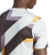 Camisa Pré-Jogo Real Madrid 2023 da Adidas Masculina. A camisa é predominantemente Wonder Silver com detalhes em azul escuro, roxo e dourado. Possui um design geométrico abstrato e moderno inspirado no clássico padrão houndstooth. A gola é careca e canela