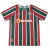 Camisa Titular do Fluminense Umbro 2024-2025. Camisa listrada em verde, branco e grená com gola V, mangas com listras e grafismo em Art Déco, escudo do Fluminense no lado esquerdo do peito, logo da Umbro no lado direito e patrocínio da Betano no centro.