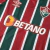 Camisa Titular do Fluminense Umbro 2024-2025. Camisa listrada em verde, branco e grená com gola V, mangas com listras e grafismo em Art Déco, escudo do Fluminense no lado esquerdo do peito, logo da Umbro no lado direito e patrocínio da Betano no centro.