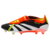 chuteira adidas Predator 24 Foldover Tongue FG Solar Energy em preto, branco, amarelo e vermelho. A chuteira está posicionada em um campo de futebol com grama verde, com uma bola de futebol ao lado. A imagem destaca o design dinâmico da chuteira, incluind