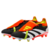 chuteira adidas Predator 24 Foldover Tongue FG Solar Energy em preto, branco, amarelo e vermelho. A chuteira está posicionada em um campo de futebol com grama verde, com uma bola de futebol ao lado. A imagem destaca o design dinâmico da chuteira, incluind