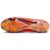 chuteira Nike Phantom GX II Elite FG Erling Haaland. A chuteira tem uma base vermelha vibrante com detalhes em azul e verde, representando as cores da bandeira da Noruega e os trajes típicos do Dia da Constituição norueguês. Possui detalhes prateados metá