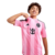 Kit Infantil Inter Miami I 2025, composto por camisa rosa com listras verticais em diferentes tons, detalhes em preto nas mangas e gola, escudo oficial do clube no peito esquerdo, logo da Adidas em preto no lado direito, patrocinador Royal Caribbean abaix