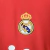 3ª Camisa Retro Adidas do Real Madrid 2011-12. A camisa é vermelha e branca com listras horizontais grossas. O escudo do Real Madrid está bordado no peito à esquerda e o logotipo da Adidas está bordado nas mangas. A camisa é usada por um jogador do Real M