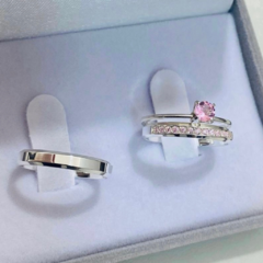 Par de alianças de prata 950 com design delicado, uma com pedra rosa e a outra lisa.