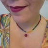 Colar Jade Mix Rondel Encanto com pedras coloridas, pendente redondo, em destaque no pescoço de uma mulher.