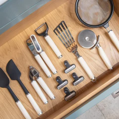 Conjunto de utensílios de cozinha KitchenAid em uma gaveta de madeira, incluindo espátulas, descascadores e outros acessórios.