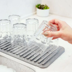 mulher colocando copos para escorrer em cima do escorredor 