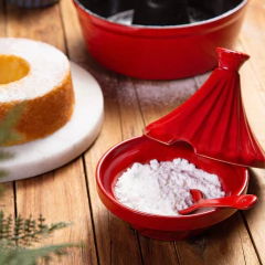 açúcareiro e saleiro de cerâmica vermelho em formato de pirâmide com tampa, base e colher em cima de uma mesa