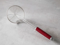 Escumadeira de metal com cabo vermelho, ideal para cozinhar.