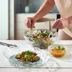 Uma pessoa servindo salada em uma tigela de sobremesa da linha Estrella Pasabahçe, com pratos de sobremesa ao lado.