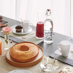 Garrafa de vidro hermética Bormioli Rocco de 1 litro em uma mesa decorada com bolo, muffins e copos.