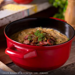 caçarola de cerâmica vermelha com o interior preto, servindo uma refeição