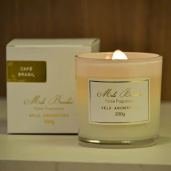 Vela aromática Café Brasil da Mels Brushes, com embalagem elegante, acesa e posicionada ao lado da caixa.