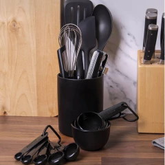 Conjunto de utensílios de cozinha KitchenAid em preto, incluindo espátula, colher, batedor e medidores, organizados em um suporte.