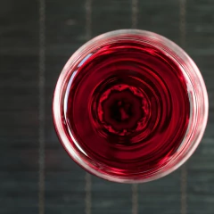 Visão superior de um copo de cristal com vinho tinto, destacando a cor vibrante da bebida.