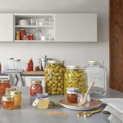 diversos potes de vidros com tampa de metal de vários tamanho em cima de bancadas e armários