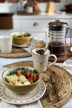cafeteira com prensa em cima de uma mesa acompanhada de uma mesa posta