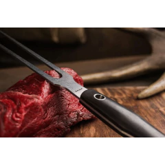 Um garfo de churrasco que está em cima de um pedaço de carne